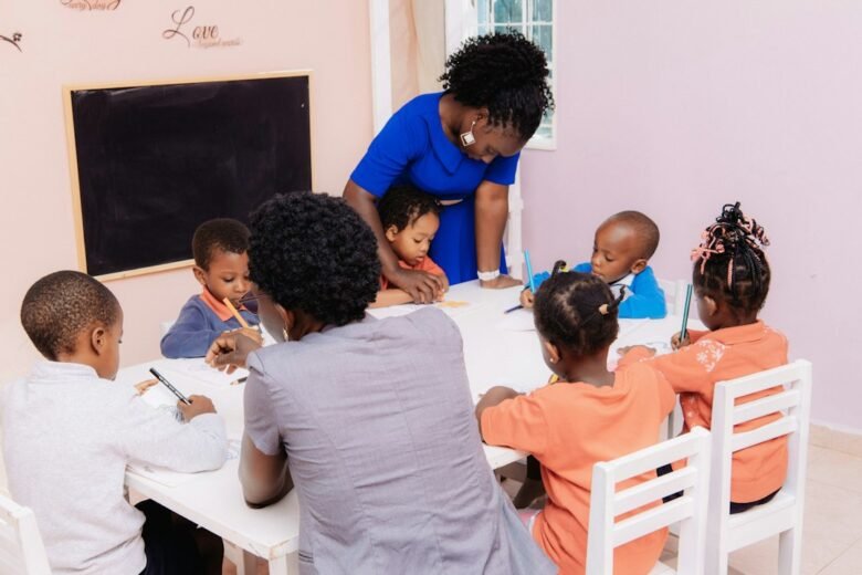 A teacher guides young children drawing at a classroom table