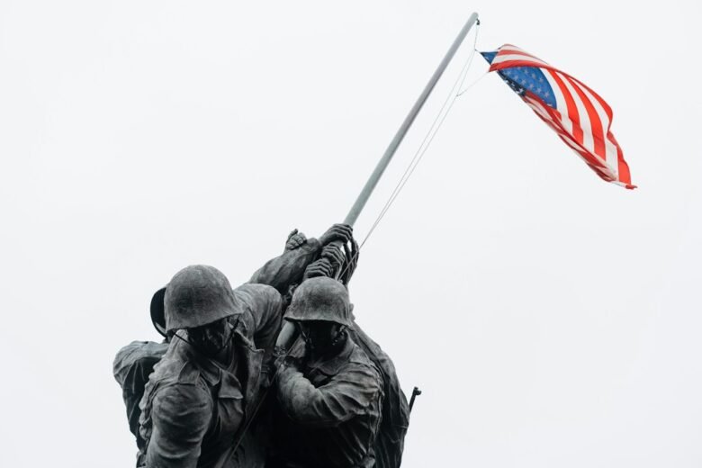 Two soldiers holding an American flag on a hilltop